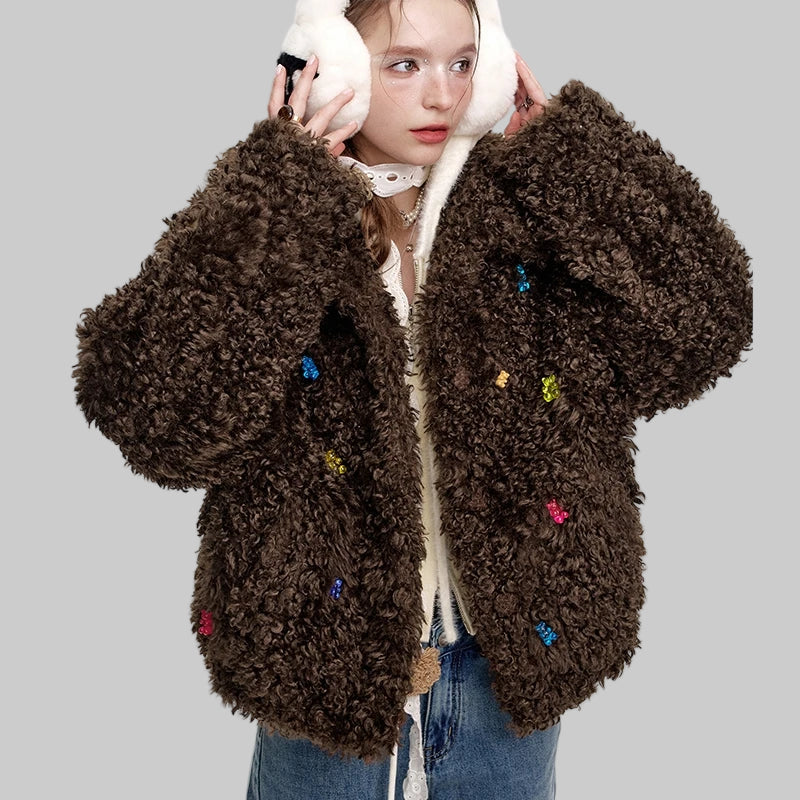 chica adolescente con vaqueros, orejeras nieve blancas y abrigo franela oversize color marrón con ositos tipo gominola cosidos