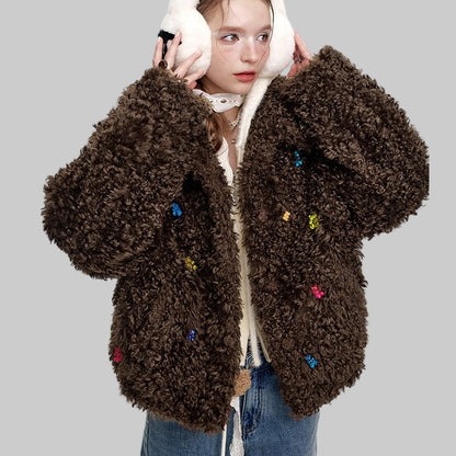 chica adolescente con vaqueros, orejeras nieve blancas y abrigo franela oversize color marrón con ositos tipo gominola cosidos